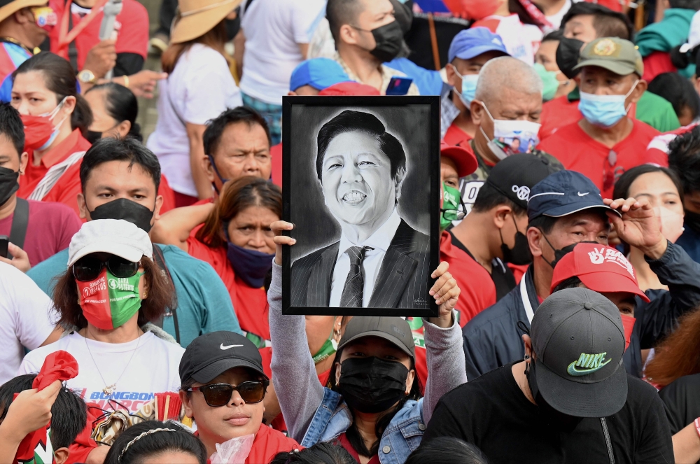 A supporter holds up a portrait of the new Philippine President Ferdinand Marcos Jr. as he is sworn into office as the country's new leader, at his inauguration ceremony at the National Museum in Manila on June 30, 2022. 