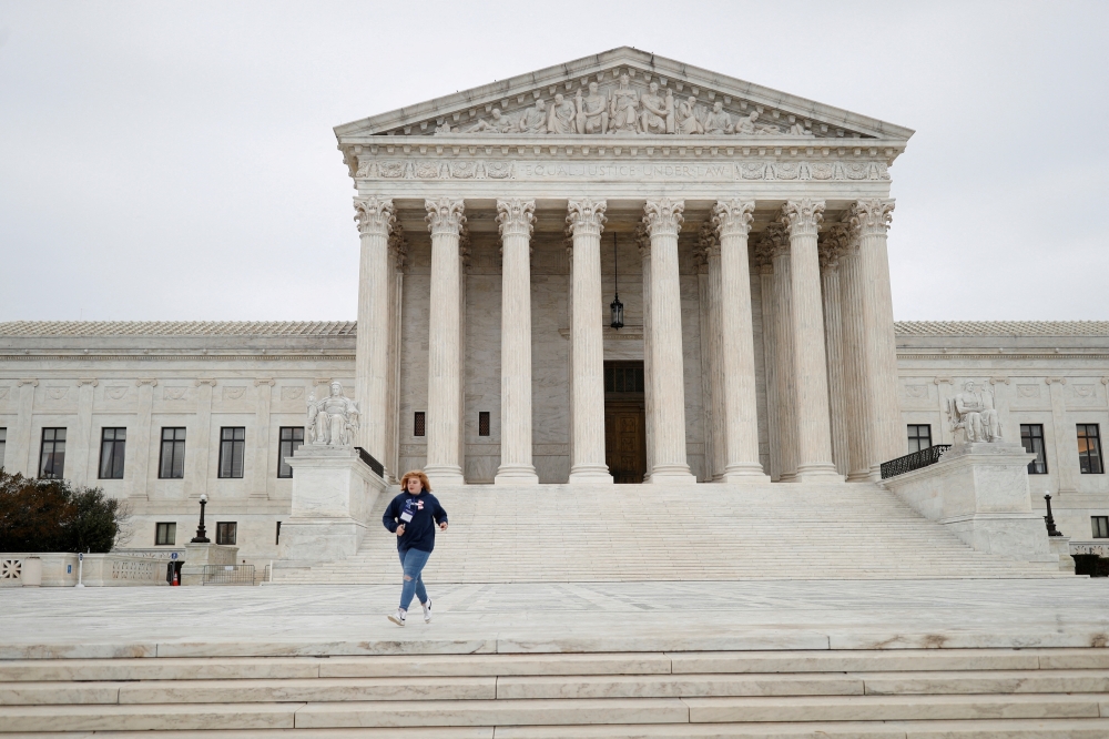 A visitor runs across the Supreme Court Plaza while attempting to catch their school group, at the US Supreme Court on Capitol Hill in Washington. -- Reuters