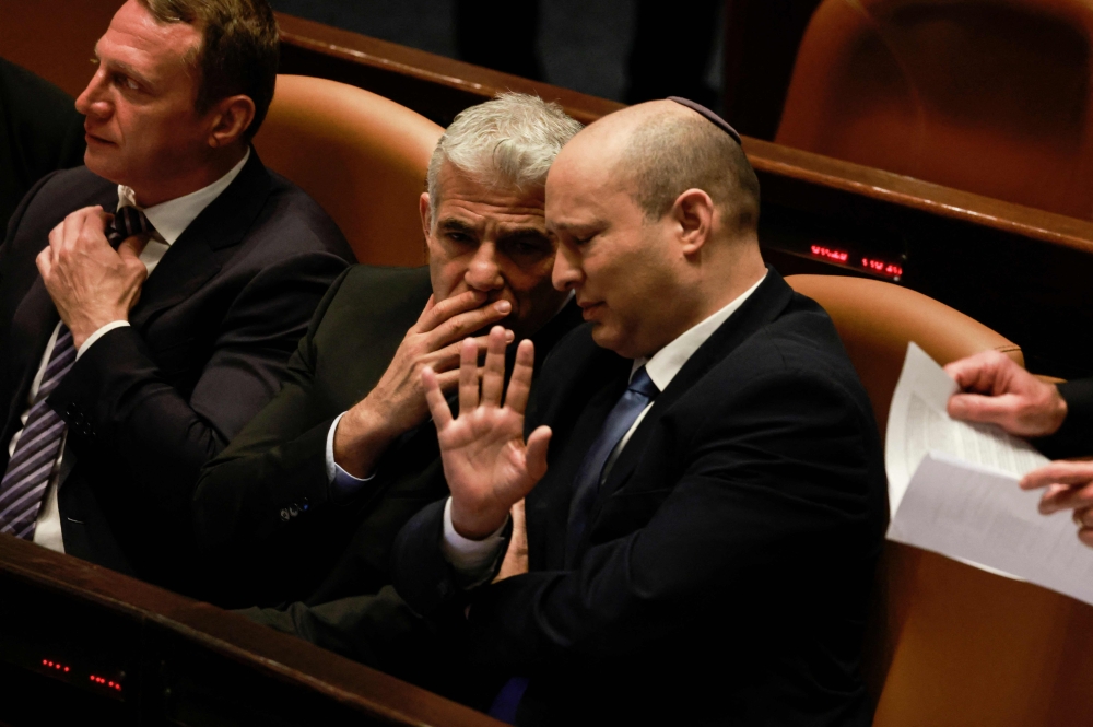 Israeli Minister of Foreign Affairs Yair Lapid (R) and outgoing Prime Minister Naftali Bennett speak to each other at the Knesset (parliament), following the dissolution of the parliament, in Jerusalem on Thursday. — AFP