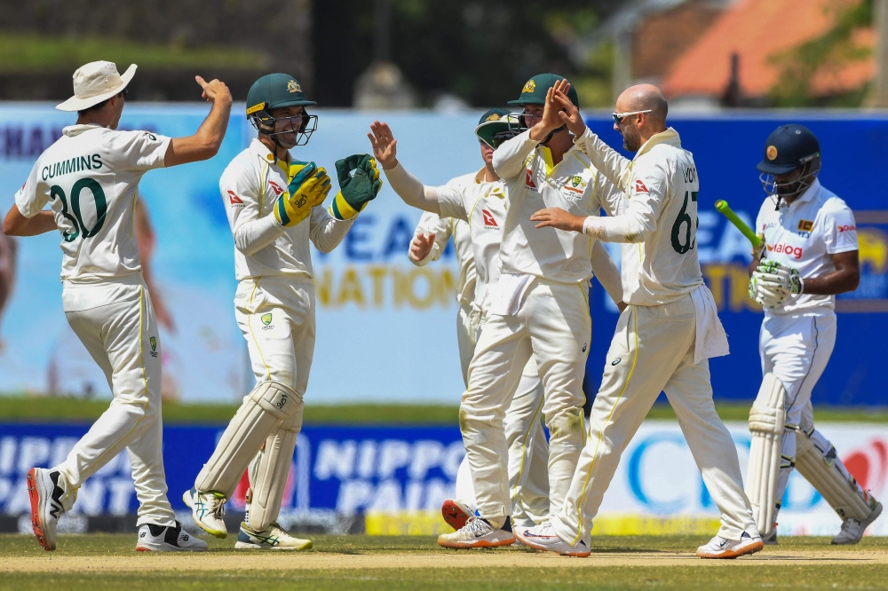 Australia's Nathan Michael Lyon (2R) celebrates with team-mates after the dismissal of Sri Lanka's captain Dimuth Karunaratne (R) during the third day of play of the first cricket Test match between Sri Lanka and Australia at the Galle International Cricket Stadium in Galle on July 1, 2022. (Photo by ISHARA S. KODIKARA / AFP)