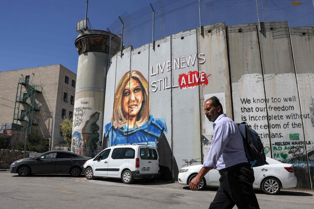 A man walks past a mural depicting slain Al Jazeera journalist Shireen Abu Akleh, who was killed while covering an Israeli army raid in Jenin in May, drawn along Israel's controversial separation barrier in Bethlehem, West Bank. - AFP