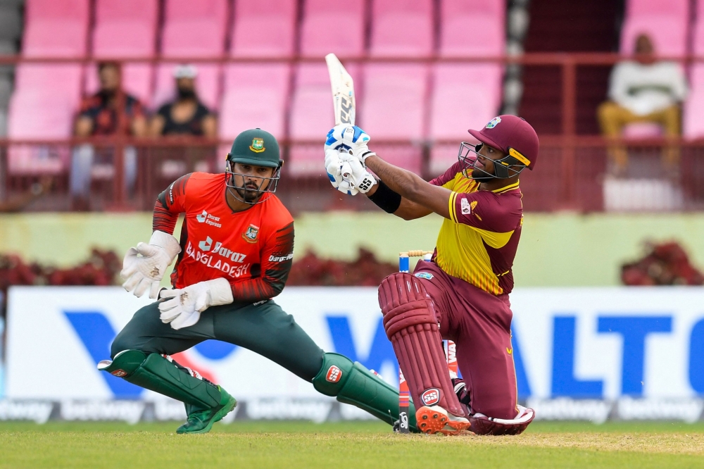 Nicholas Pooran (R) of West Indies hits a six and Quazi Nurul Hasan Sohan (L) of Bangladesh attempts to catch him. -- AFP