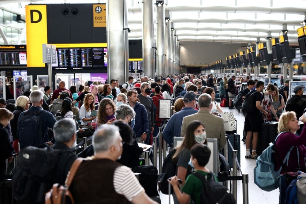 Passengers queue inside the departures terminal of Terminal 2 at Heathrow Airport in London. - Reuters File