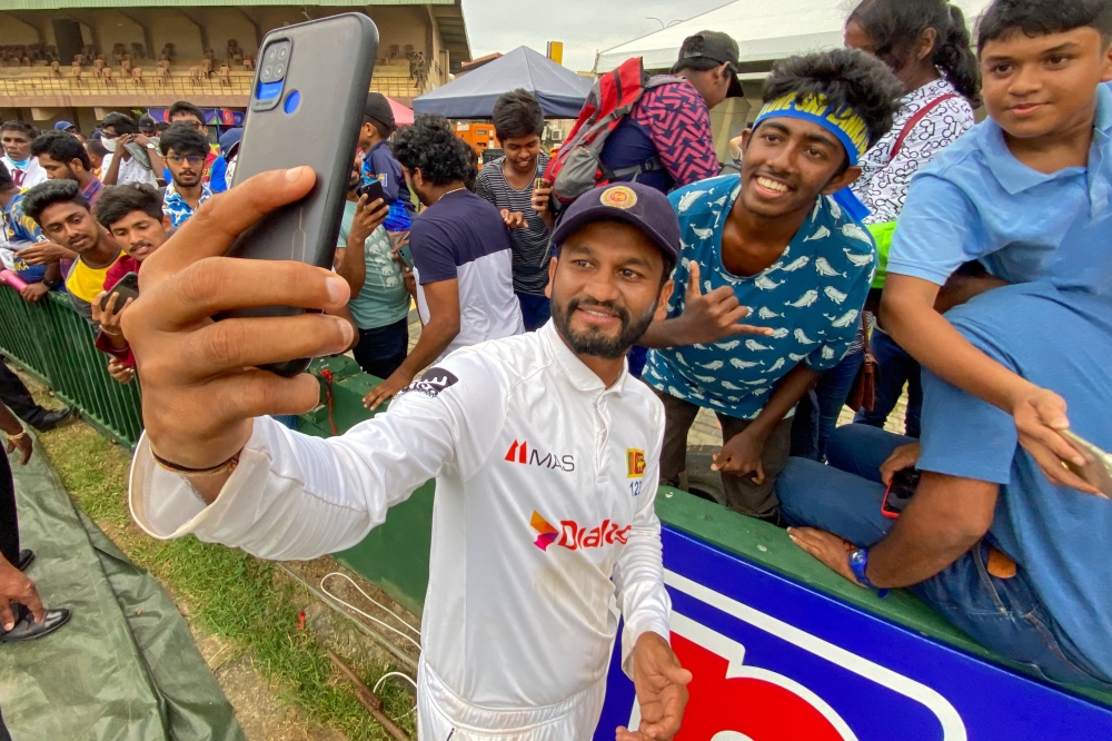 Sri Lanka's captain Dimuth Karunaratne takes a selfie with fans after winning the second Test at the Galle International Cricket Stadium in Galle. -- AFP