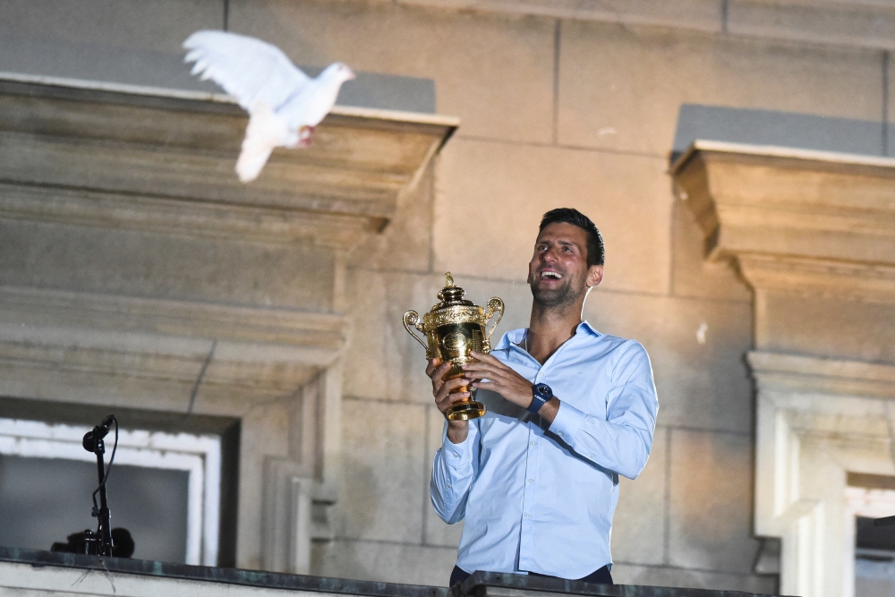 Novak Djokovic holds up the Wimbledon trophy and greets fans during a welcoming ceremony in front of the city hall in Belgrade. -- Reuters