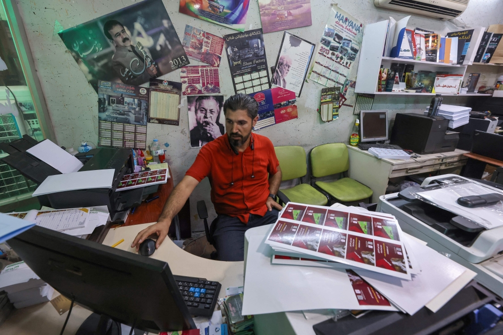 Iraqi Kurd Haresh Talib works at his desk at a printing house in Iraq's northeastern city of Sulaymaniyah in the autonomous Kurdistan region. -- AFP
