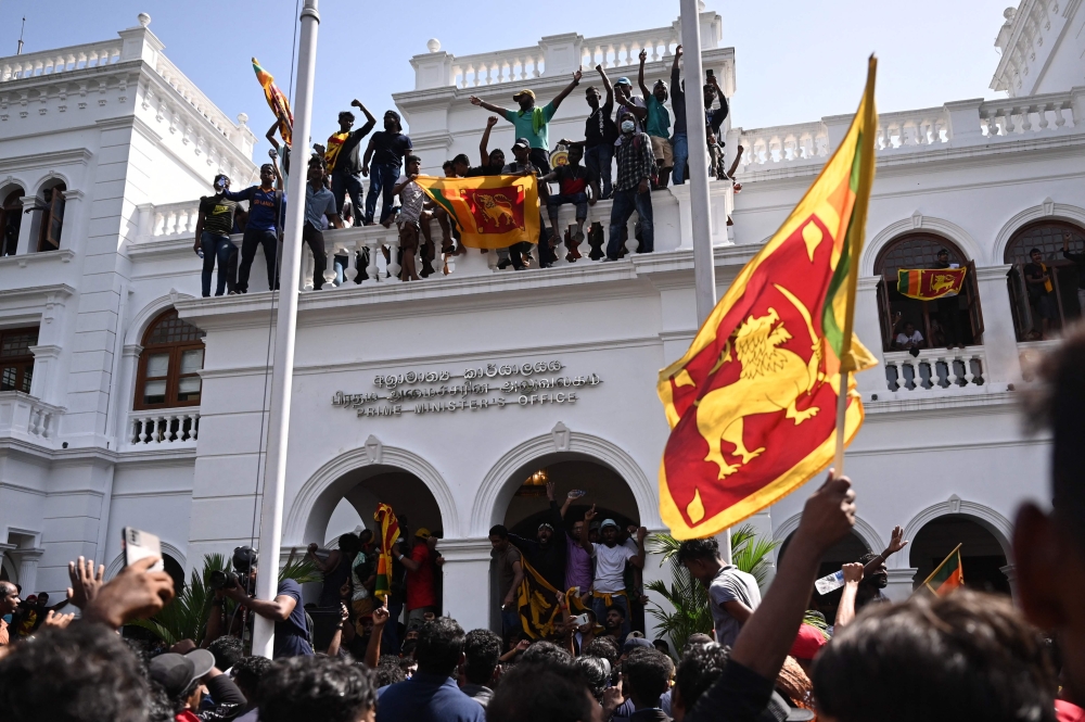 Demonstrators shout slogans and wave Sri Lankan flags during an anti-government protest inside the office building of prime minister in Colombo. —  AFP