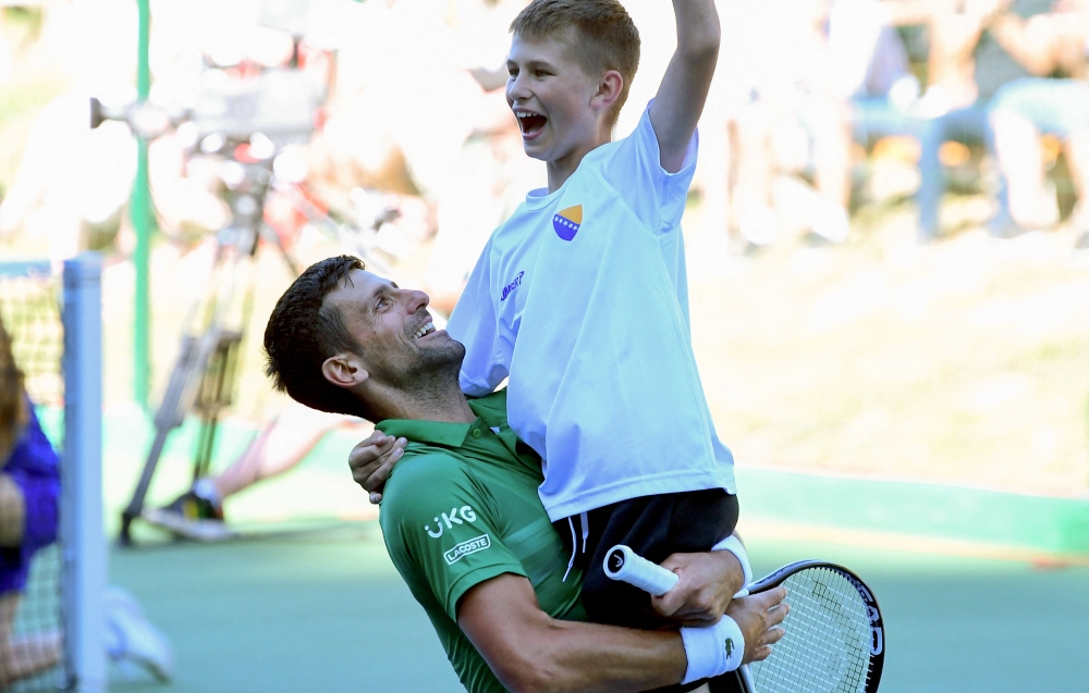 Novak Djokovic holds a Bosnian boy celebrating during an exhibition match, organised to mark the opening of a tennis court at the "Archaeological park of the Bosnian pyramid" near Visoko. -- AFP