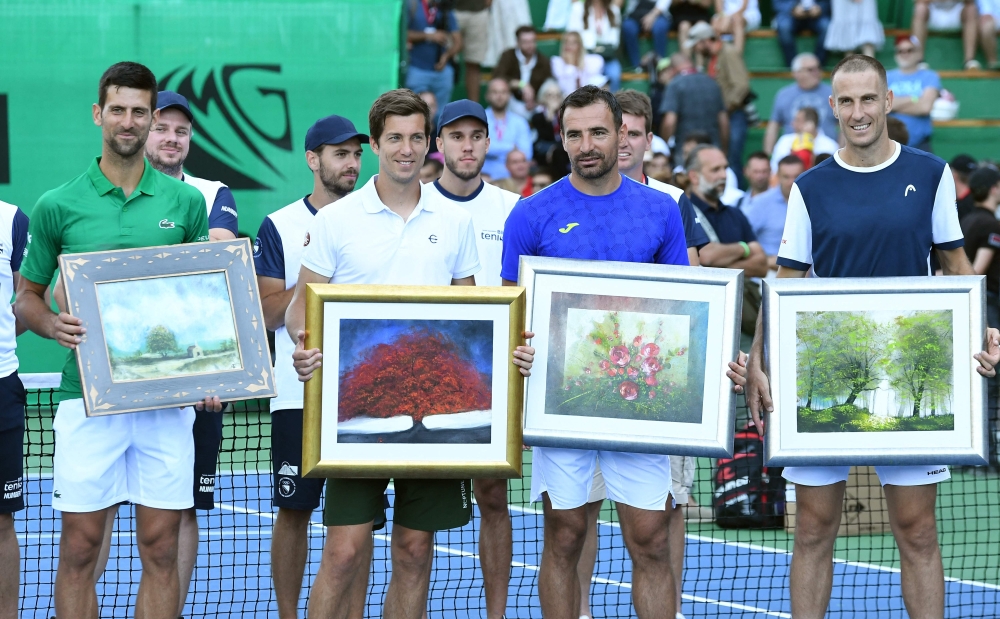 Novak Djokovic (L), Aljaz Bedene from Slovenia (2nd L), Ivan Dodig from Croatia (2nd R) and Bosnian player Aldin Setkic (R) pose with theirs gifts after an exhibition match. -- AFP