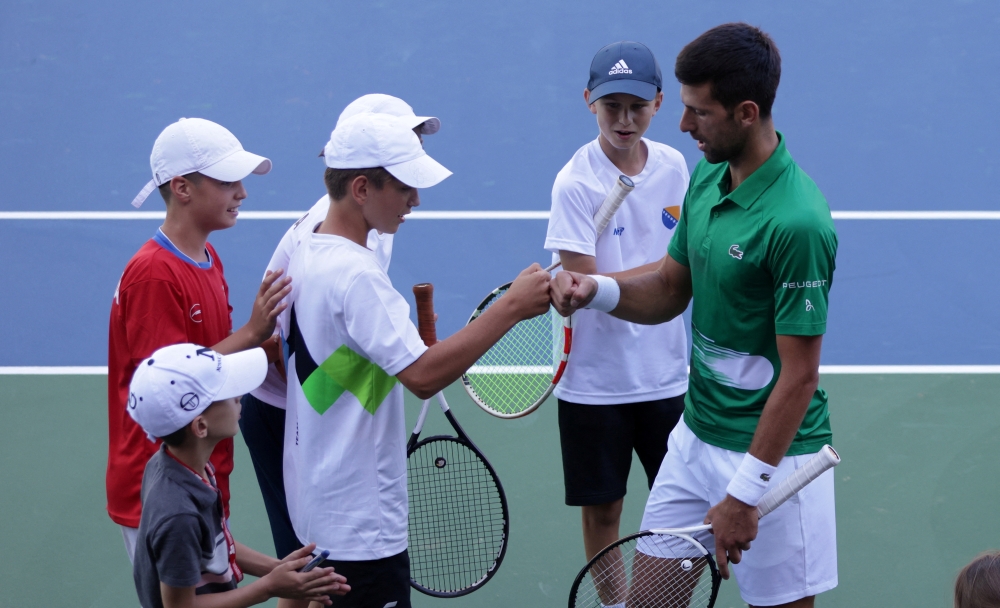 Novak Djokovic bumps fists with a boy during the opening of a regional tennis centre. -- Reuters