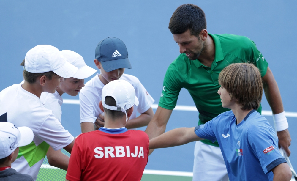 Novak Djokovic bumps fists with a boy during the opening of a regional tennis centre. -- Reuters