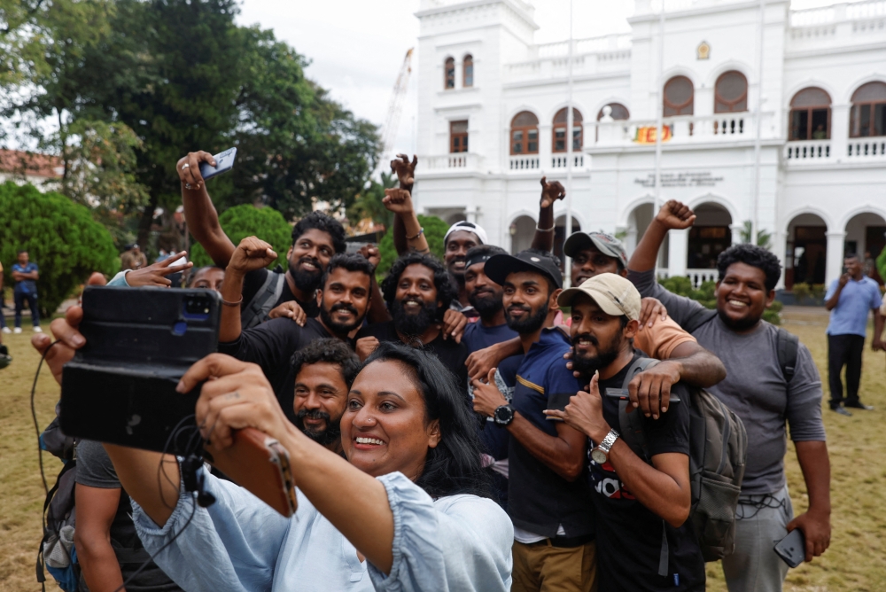 Protesters take a selfie before vacating Prime Minister Ranil Wickremesinghe's office in Colombo on Thursday. -- Reuters