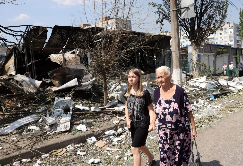 Two person walk among the debris of a destroyed local market after a Russian missile strike in the town of Bakhmut, Donetsk region on July 16, 2022 amid Russian military invasion of Ukraine.  (Photo by Anatolii Stepanov / AFP)
