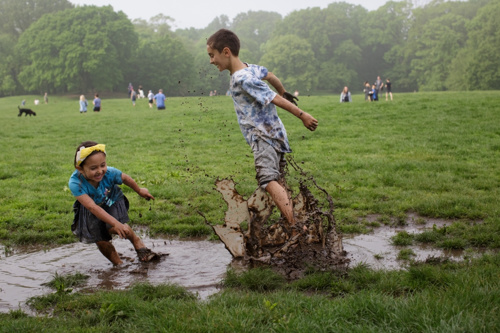 Siblings Naima, 4, and David, 8, play in mud puddles at Prospect Park on a warm Saturday morning in Brooklyn.