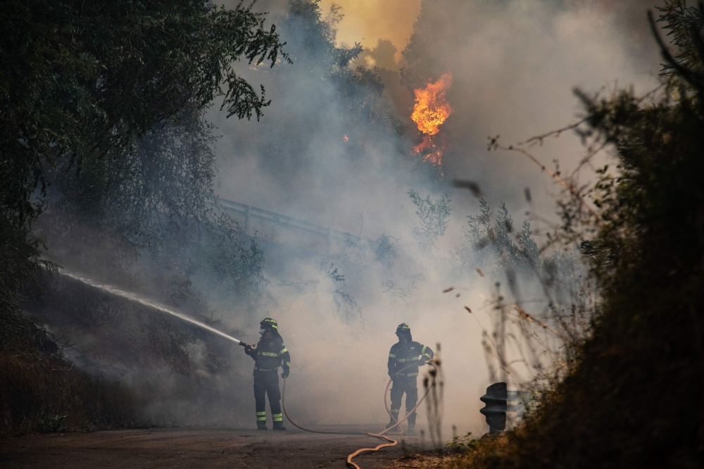 Firefighters try to put out a fire near the city of Massarosa, central Italy, on Wednesday. -- AFP
