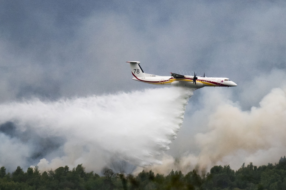 A De Havilland Canada Dash 8-400 MR aircraft drops water over a wildfire raging in the Monts d'Arree, near Brennilis, Brittany, on July 20, 2022.