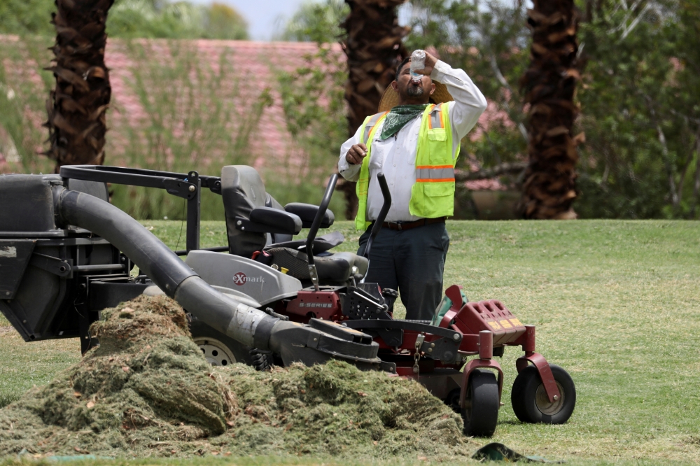A landscaper drinks water in temperatures that have reached well above triple digits in Palm Springs, California, U.S. July 20, 2022. 