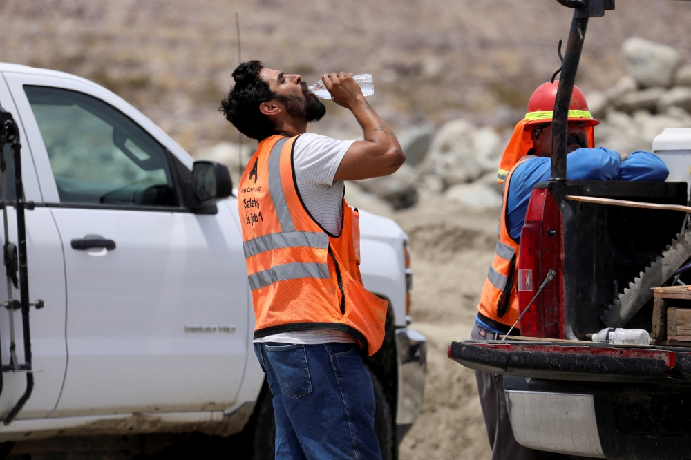 A contruction worker drinks water in temperatures that have reached well above triple digits in Palm Springs, California, U.S. July 20, 2022.  