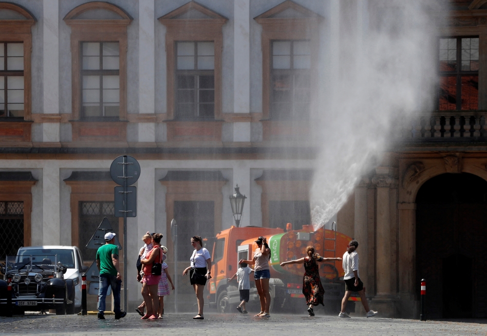 People are sprayed with water to cool down as temperature hovered over 34 degrees Celsius (93.2 degrees Fahrenheit), in Prague, Czech Republic, July 20, 2022. 