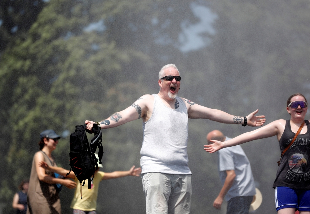 People are sprayed with water to cool down as temperature hovered over 34 degrees Celsius (93.2 degrees Fahrenheit), in Prague, Czech Republic, July 20, 2022. 