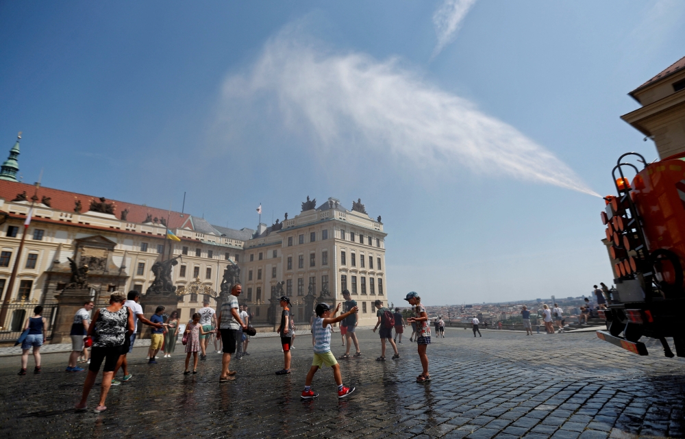 People are sprayed with water to cool down as temperature hovered over 34 degrees Celsius (93.2 degrees Fahrenheit), in Prague, Czech Republic, July 20, 2022.