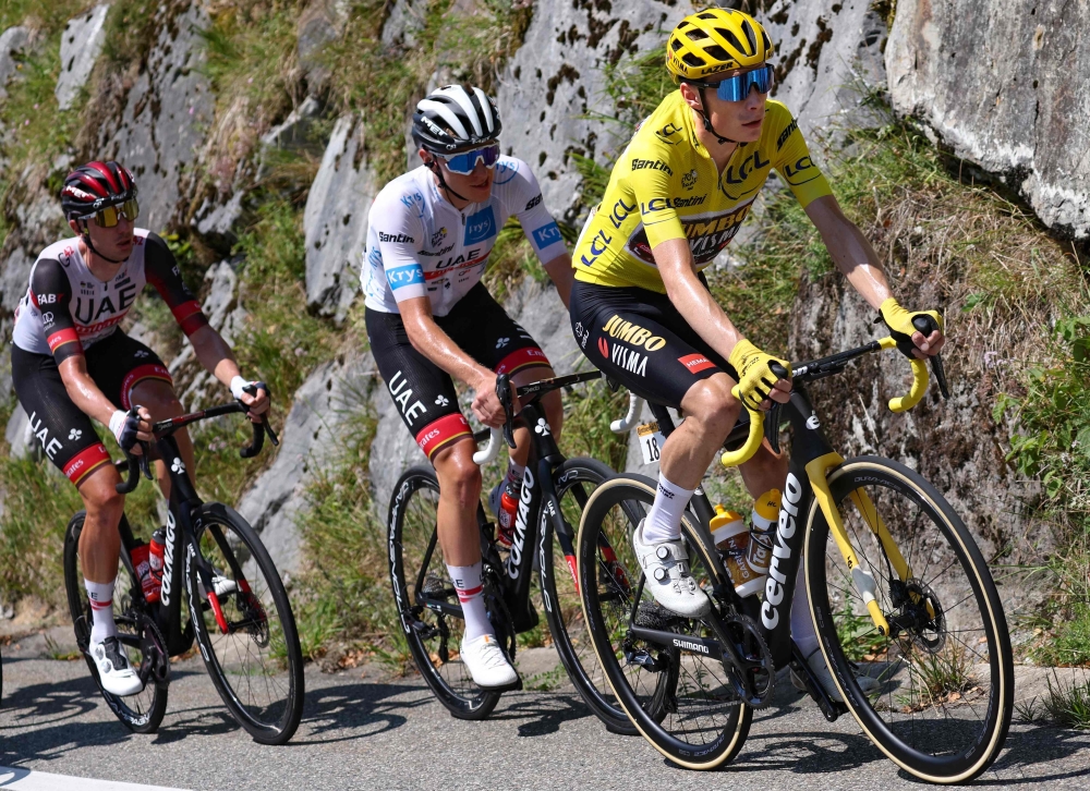 Jumbo-Visma team's Danish rider Jonas Vingegaard wearing the overall leader's yellow jersey (R) and UAE Team Emirates team's Slovenian rider Tadej Pogacar wearing the best young rider's white jersey (2nd L) cycle with the pack of riders in the ascend of Col d'Aubisque during the 18th stage of the 109th edition of the Tour de France cycling race, 143,2 km between Lourdes and Hautacam in the Pyrenees mountains in southwestern France, on July 21, 2022. (Photo by Thomas SAMSON / AFP)

