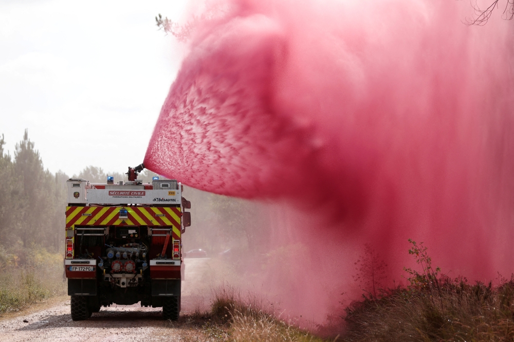 Firefighters spray flame retardant to extinguish ground fire on land in Hostens in the Gironde region of southwestern France on Friday. - Reuters