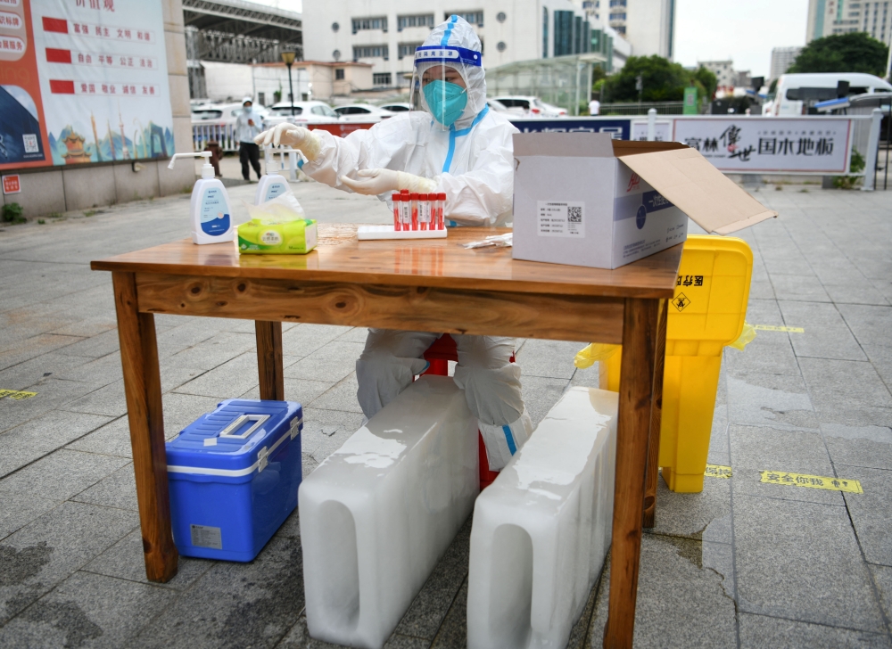A medical worker in a protective suit sits with ice blocks at a nucleic acid testing site during preparations to test residents for Covid-19, amid a heatwave warning in Nanchang, Jiangxi province, China. - Reuters 