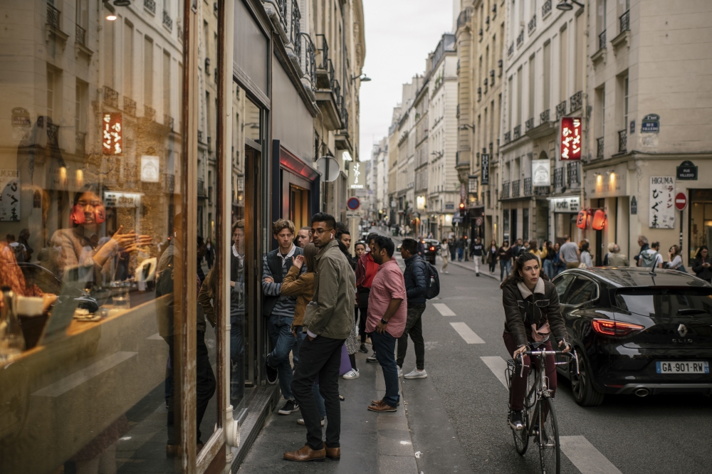 People stand in line to enter a restaurant in Paris, on May 25, 2022. (Dmitry Kostyukov/The New York Times)