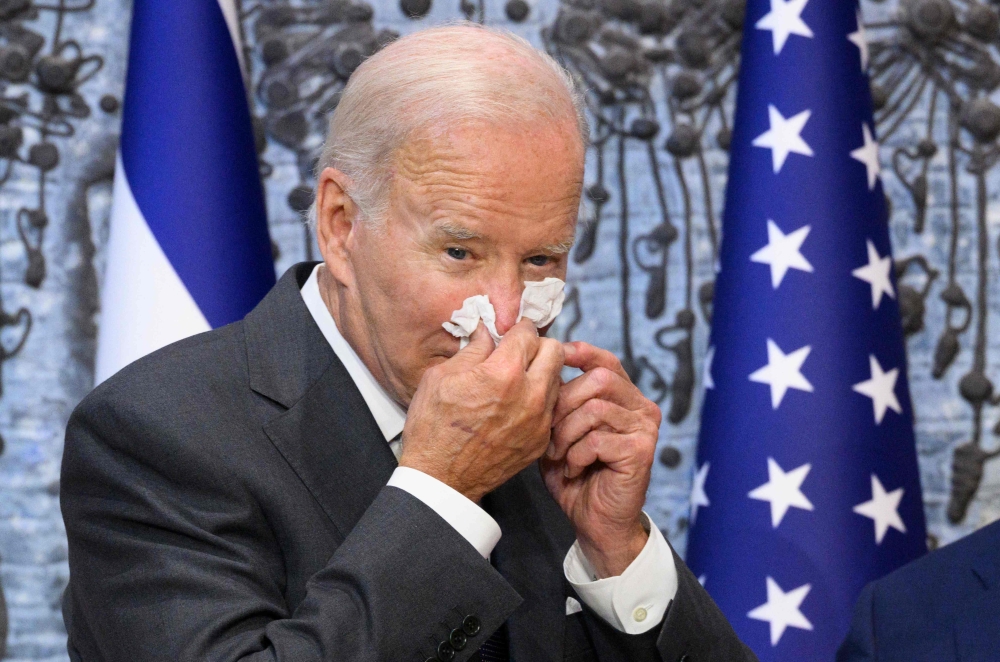 (FILES) In this file photo taken on July 14, 2022, US President Joe Biden wipes his nose after signing the guest book while visiting Israel's President Isaac Herzog at Beit HaNassi, the presidential residence in Jerusalem. Biden said on July 21, 2022, he was "doing great" after the White House announced he had contracted Covid-19 and was isolating with mild symptoms. "Folks, I'm doing great," Biden tweeted, above a picture showing him seated at his desk, smiling, with smartphones and documents laid out in front of him. "Thanks for your concern," the president wrote, adding: "Keeping busy!" (Photo by MANDEL NGAN / AFP)
