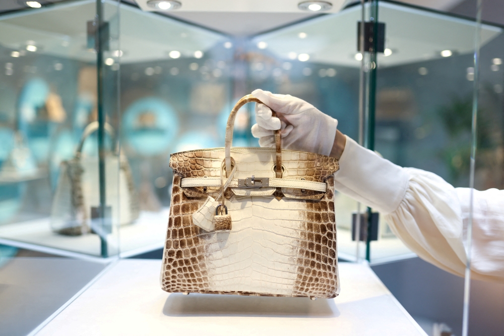 A specialist at Christie's Handbags & Accessories poses with a piece titled 'A rare, matte white himalaya niloticus crocodile Birkin 25 with palladium hardware, Hermes, 2013' which is on display as part of "Handbags Online: The London Edit" at Christie's in London, Britain. - Reuters file photo