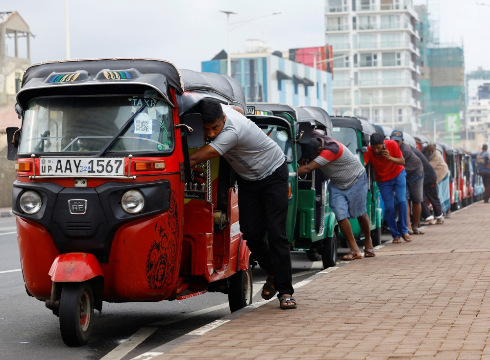 Drivers push auto rickshaws in a line to buy petrol from a fuel station, amid Sri Lanka's economic crisis, in Colombo on Friday. - Reuters