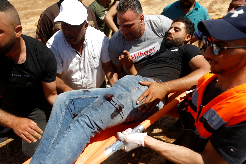 People carry an injured Palestinian during a protest against Israeli settlement activity in Al Mughayyer village, in the Israeli-occupied West Bank on Friday. - Reuters