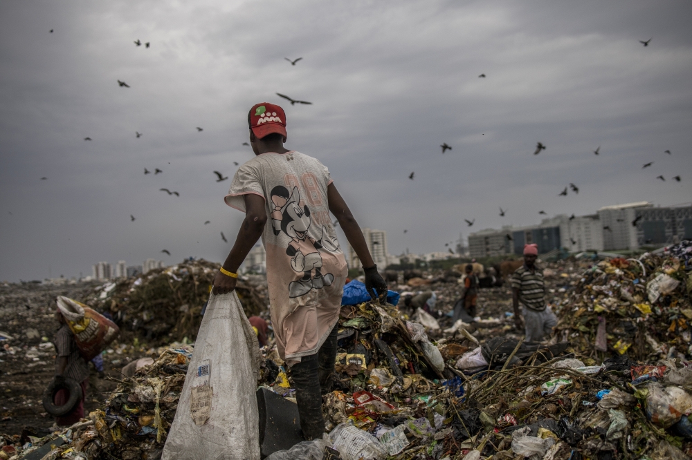 A ragpicker hunts for useful plastic items at a garbage dump in Chennai, India, July 7, 2022. (Anindito Mukherjee/The New York Times)