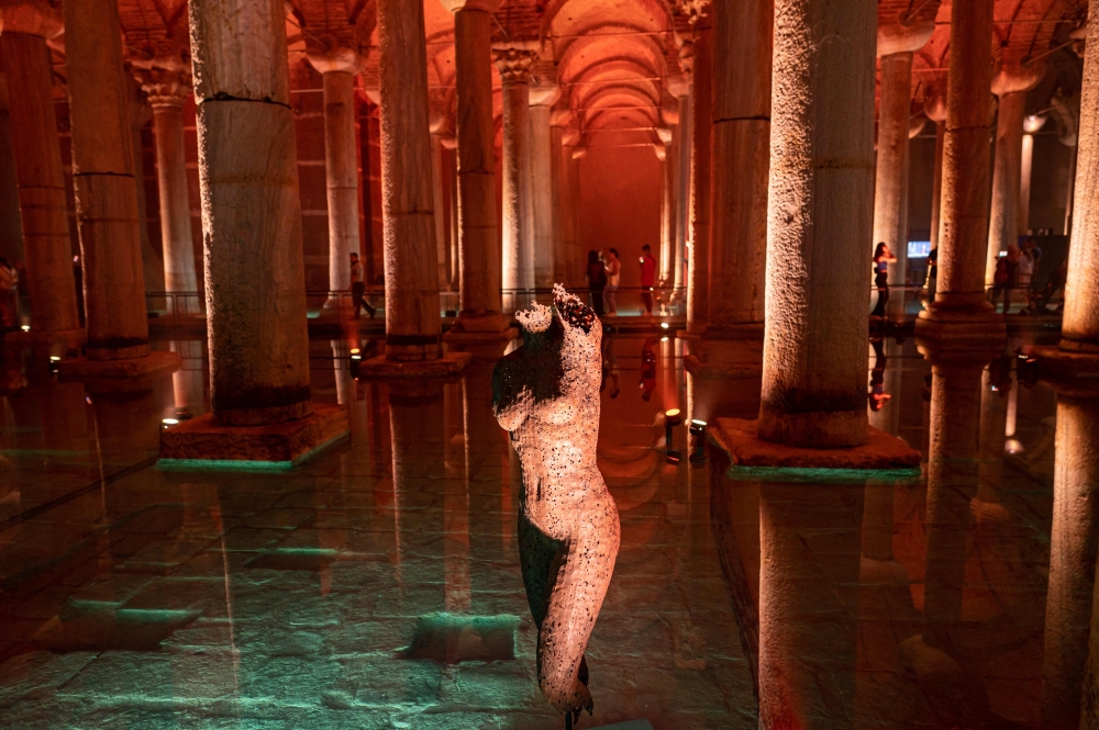 People visiting the Basilica Cistern historic site in Istanbul, Turkey, on July 26, 2022. Built in 542 and resting near the Hagia Sophia -- then a cathedral, now a mosques -- the basilica was once part of a network of more than 100 cisterns begun by the Romans and completed by the Byzantians and Ottomans to supply the city and its palaces with running water. (Photo by Yasin AKGUL / AFP)
