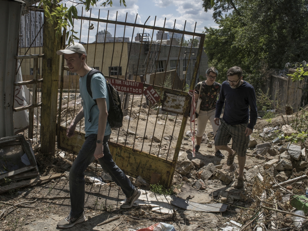 Environmental activist Ihor Sumliennyi, left, and friends, look for military artifacts at a site hit by a Russian cruise missile in Kyiv, Ukraine. 
