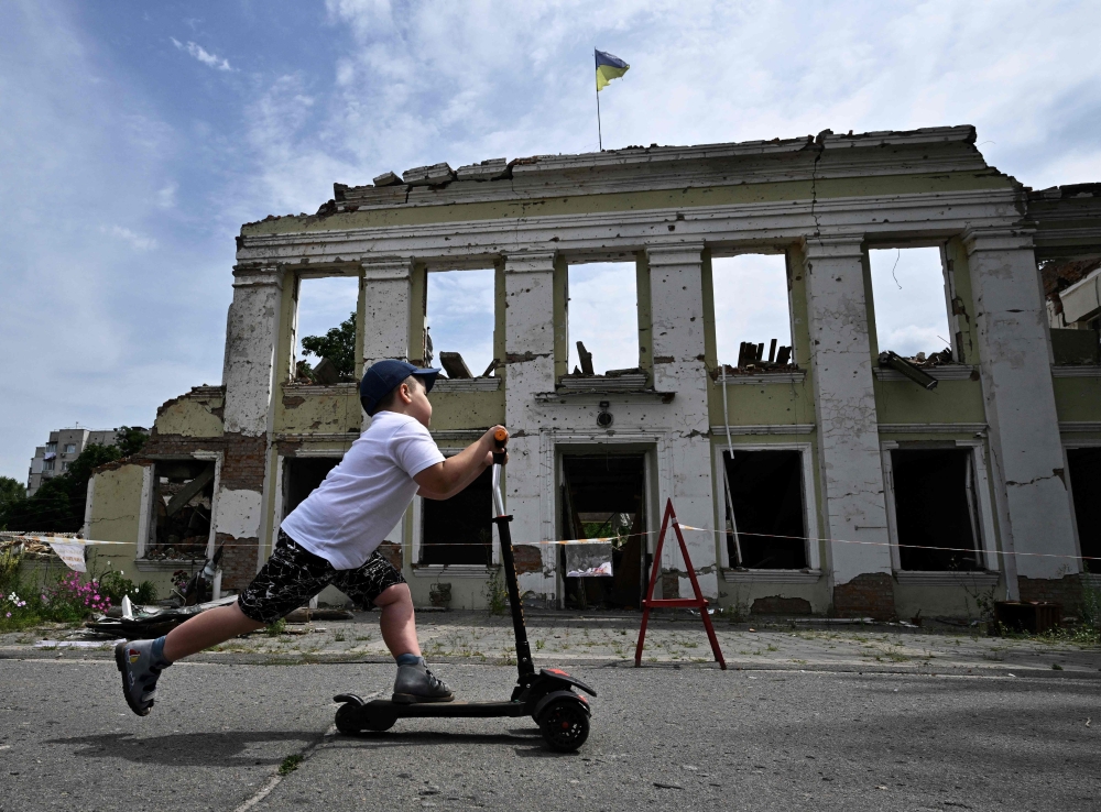 A boy ride his scooter in front of the destroyed building of the city hall in the city of of Okhtyrka, Sumy region amid the Russian attack on Ukraine. -- AFP