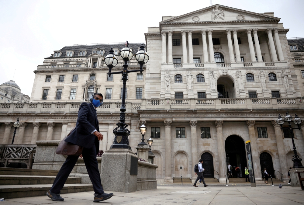 A person walks past the Bank of England in the City of London financial district. - Reuters