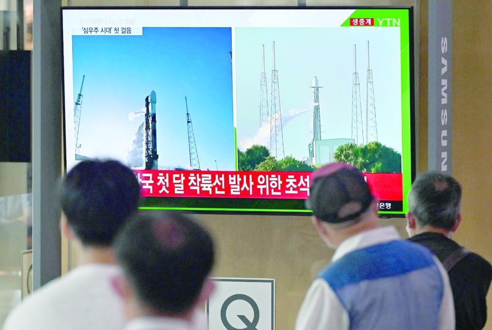People watch a television screen showing a live footage of a SpaceX Falcon 9 rocket launching with South Korea's first lunar orbiter Danuri onboard from Cape Canaveral in Florida, at a railway station in Seoul on August 5, 2022. (Photo by Jung Yeon-je / AFP)
