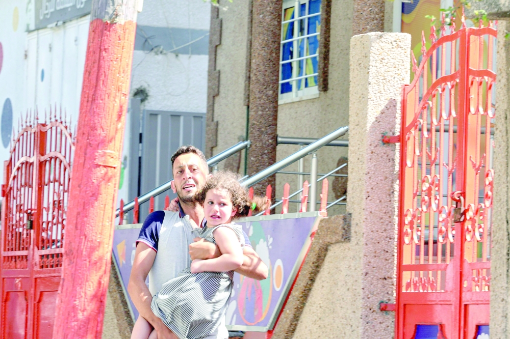 A Palestinian man carries his daughter after evacuating his home during an Israeli air strike in Gaza City on Sunday. -- AFP