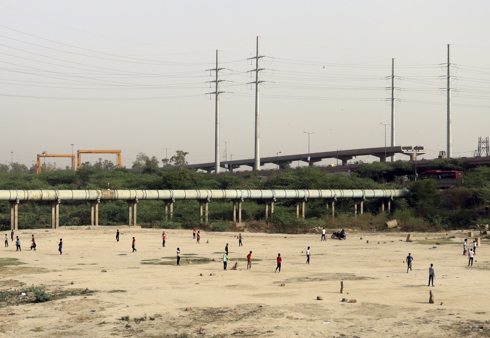 Children play cricket on vacant land in New Delhi, on June 11, 2022. (Anindito Mukherjee/The New York Times)