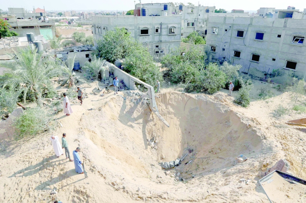 Palestinians inspect a crater in Rafah. -- AFP

