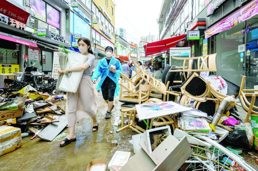 Pedestrians walk past debris outside shops at the historic Namseong Market in the Gangnam district of Seoul on Tuesday, after record-breaking rains caused severe flooding. - AFP