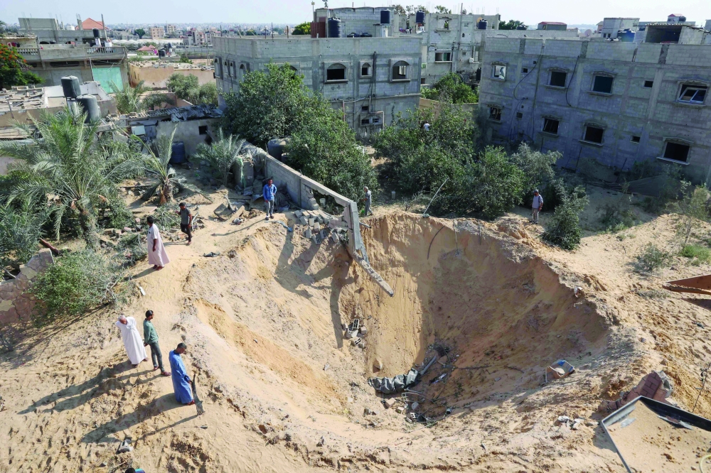 Palestinians inspect a crater following the latest three days of conflict with Israel ahead of a truce, in Rafah town in the southern Gaza Strip. - AFP