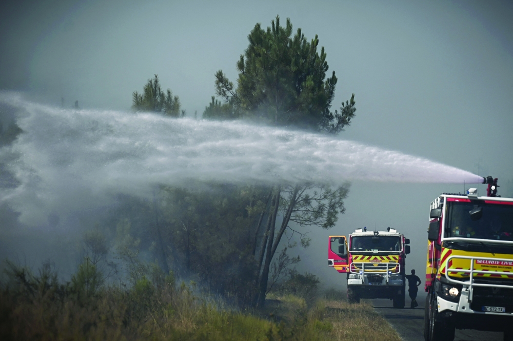Firefighters use water cannon to extinguish a forest fire near Saint-Magne, southwestern France on Wednesday. -- AFP