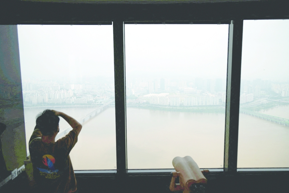 A man looks at flooded Han river from an observation platform in Seoul on Thursday. - Reuters