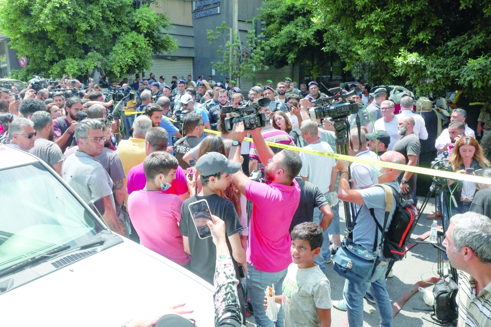 Members of the media and other people stand together outside the Federal Bank of Lebanon where a man, who security sources said is armed, holds the staff hostage while demanding the return of his bank deposits, in Hamra, on Thursday. - Reuters