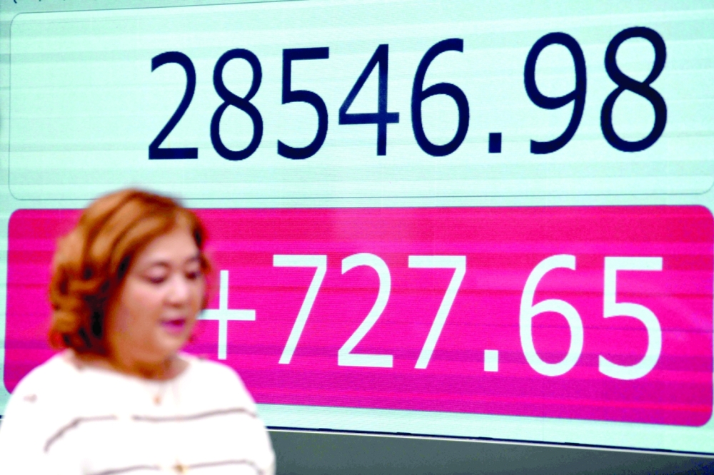 A woman walks past the closing numbers on the Tokyo Stock Exchange in the business district of Tokyo on Friday, following recent gains on Wall Street. -  AFP