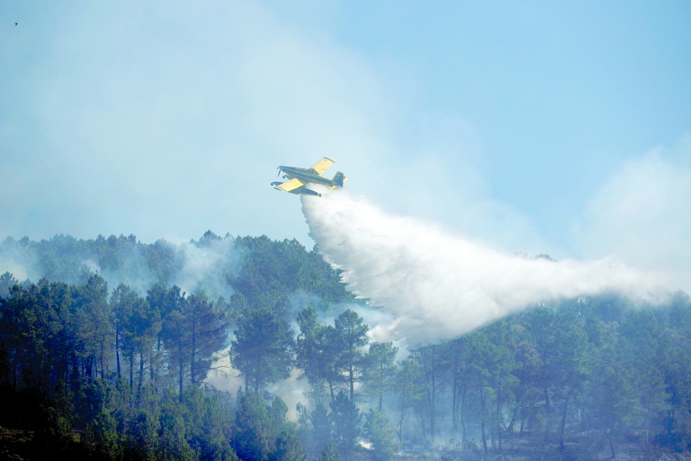 An airplane drops water onto a wildfire in Videmonte, Celorico da Beira, Portugal, on Friday. - Reuters