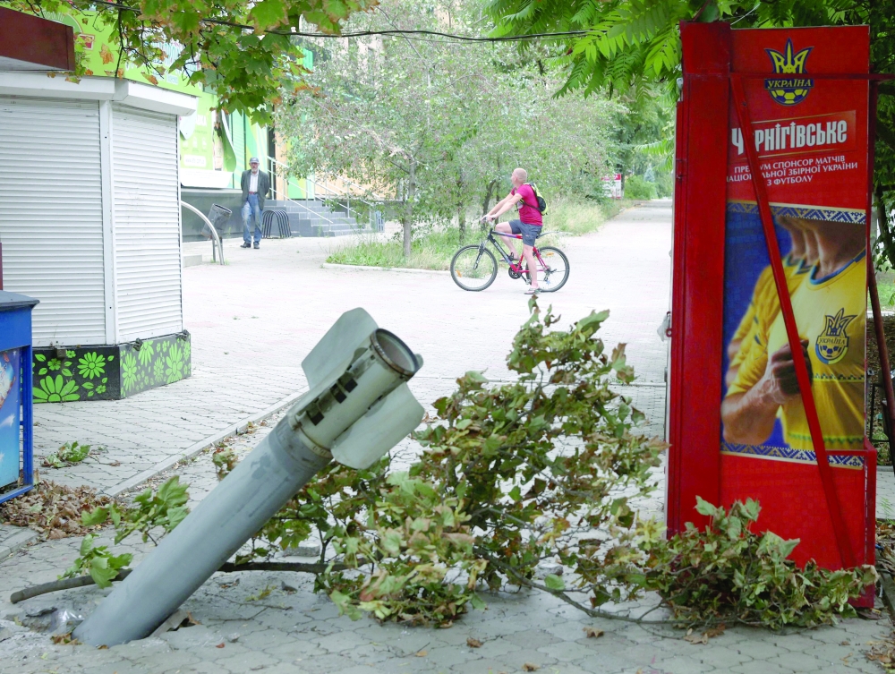 A resident rides bicycle past a fragment of a rocket embedded in the ground following a rocket attack in the town of Bakhmut, Donetsk region, on Friday. - AFP